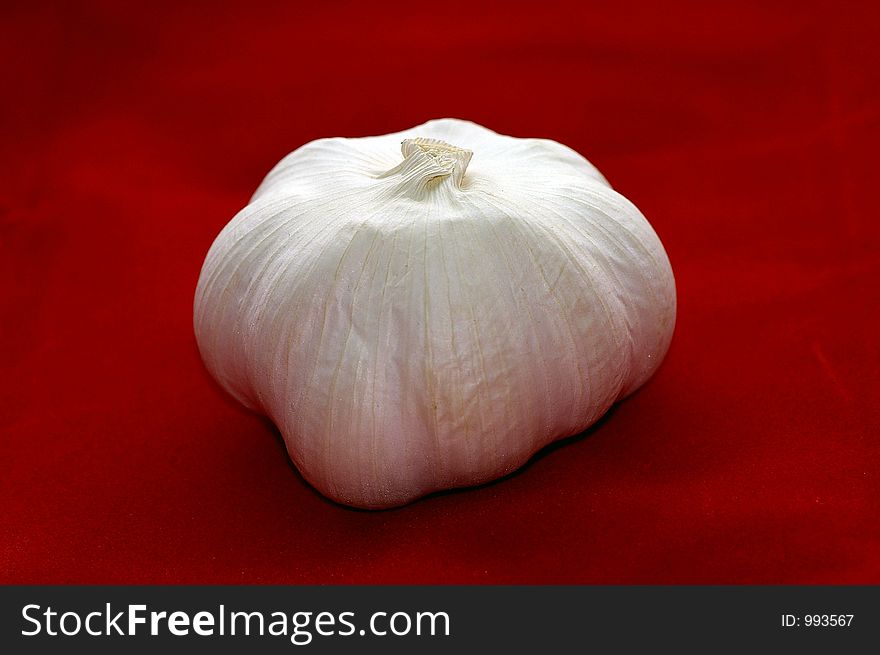 Closeup of a garlic bulb against a red background. Closeup of a garlic bulb against a red background