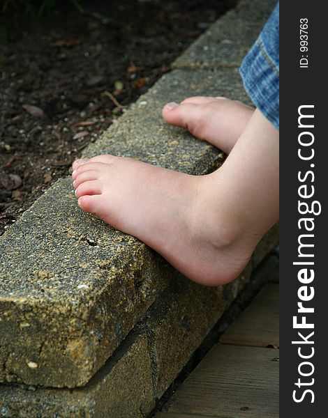 Childs feet resting on a brick wall