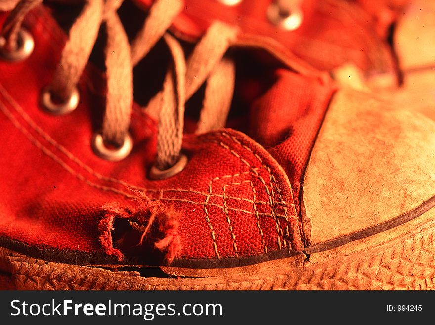 Detail of red canvas shoe with worn area. Detail of red canvas shoe with worn area