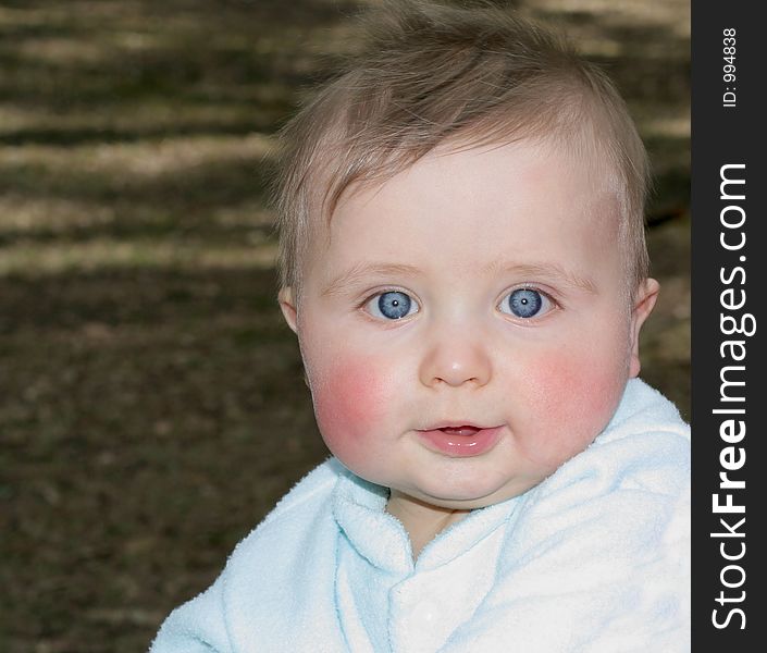 Baby boy with amazing blue eyes sitting in the park. Baby boy with amazing blue eyes sitting in the park.