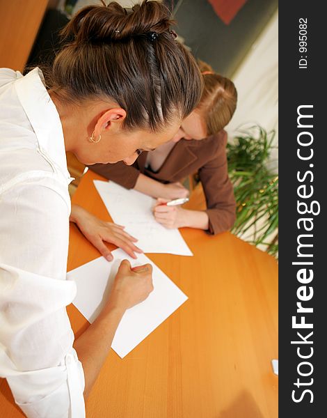 Two business women taking notes in the office. Two business women taking notes in the office