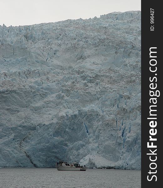 Small tourist boat at the foot of a glacier in Alaska. Small tourist boat at the foot of a glacier in Alaska.