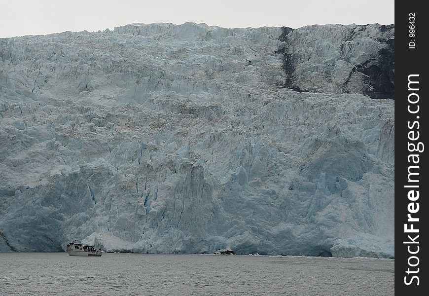 Small tourist boat at the foot of a glacier in Alaska. Small tourist boat at the foot of a glacier in Alaska.