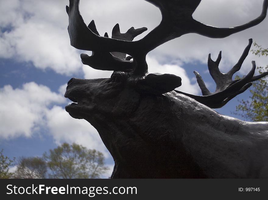 Statue of a caribou silloutted on the sky.