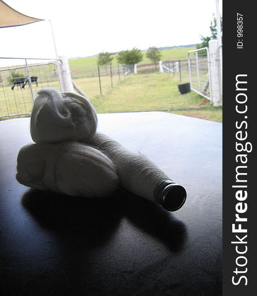 Backdrop of farm with Alpaca roving and spindle of thread on a table