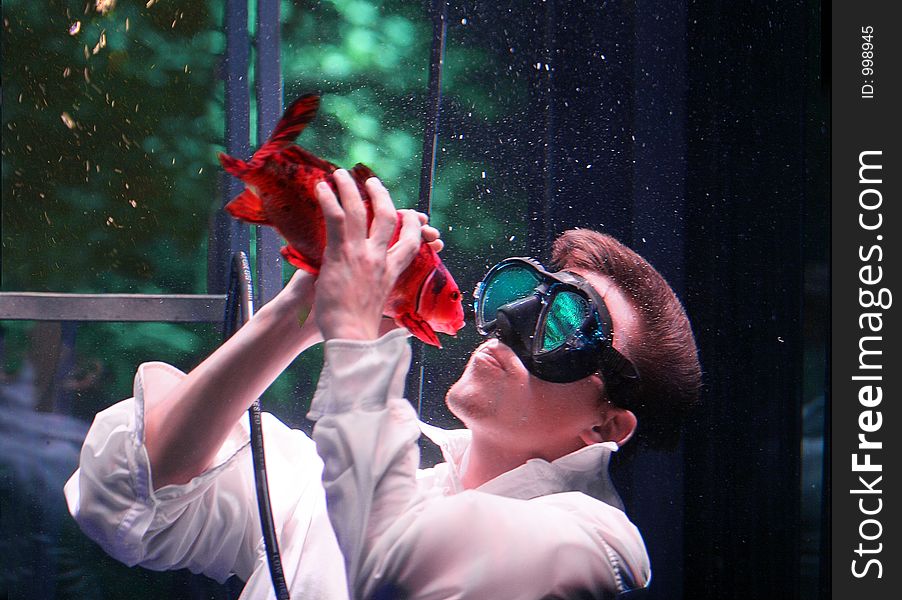 Young man kissing fish underwater