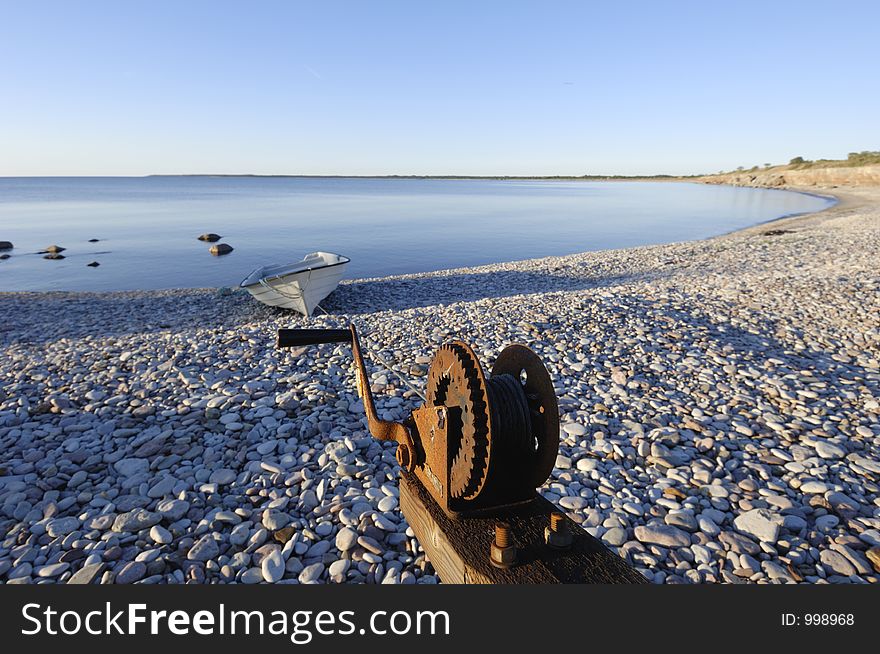 Small boat fastened in winch on stony beach, with sea in background at earle sunset. Small boat fastened in winch on stony beach, with sea in background at earle sunset