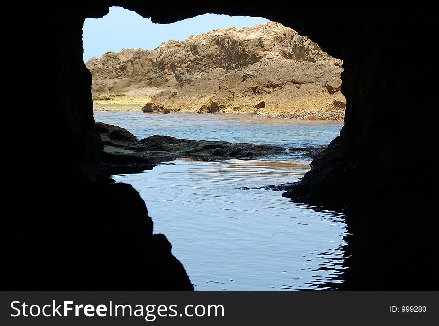 Silhouette inside of cave viewing the sea in front of its open mouth. Silhouette inside of cave viewing the sea in front of its open mouth