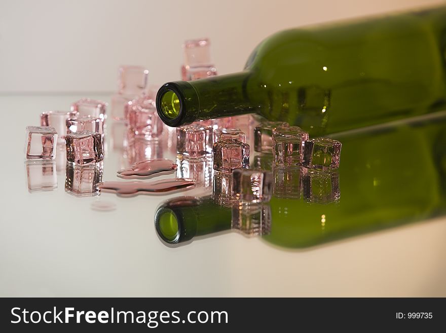 Botle with ice cubes and some spilled red wine on a reflecting surface. Botle with ice cubes and some spilled red wine on a reflecting surface.