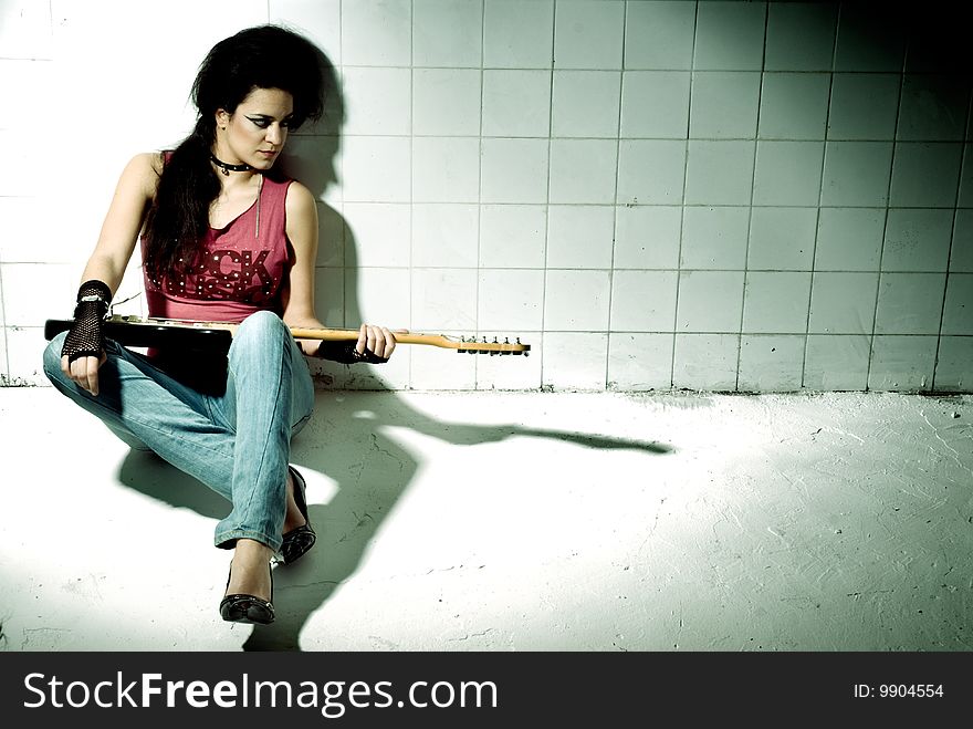 Punk Girl playing guitar on an underground background high contrast. Punk Girl playing guitar on an underground background high contrast