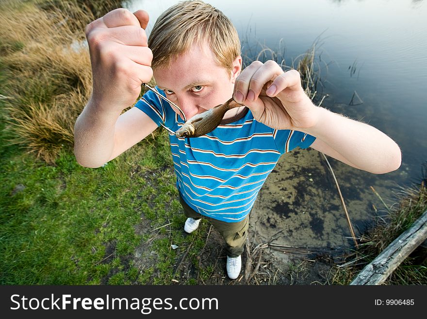 A cute guy showing a fish. A cute guy showing a fish