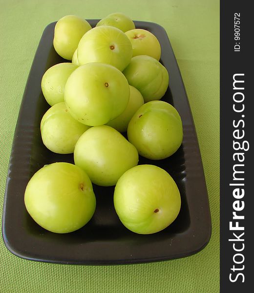 Green plums on a black plate