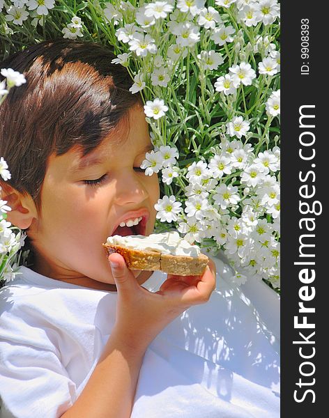 A little kid holding bread with white cream on. A little kid holding bread with white cream on