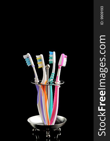 Four colorful toothbrushes isolated on black