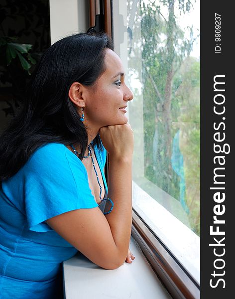 Beautiful Hispanic young woman looking out of a window