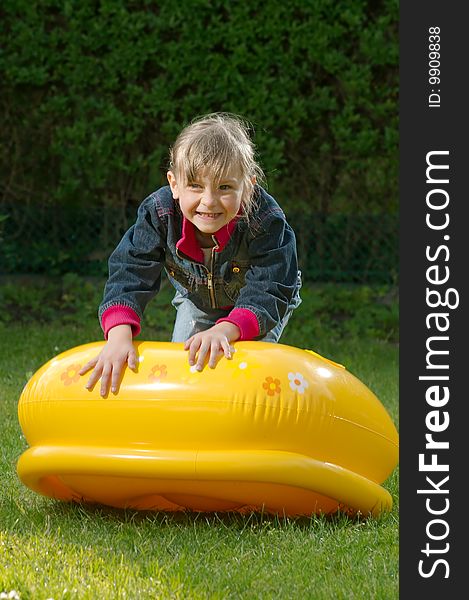 Young girl is climbing on the blowed toy