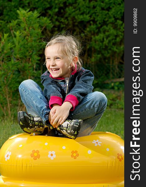 Young girl is sitting on the blown toy