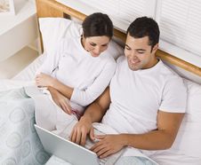 Couple Relaxing In Bed And Looking At A Laptop Royalty Free Stock Photos