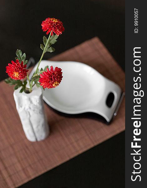 Interior detail of vase with red flowers and candy bowl