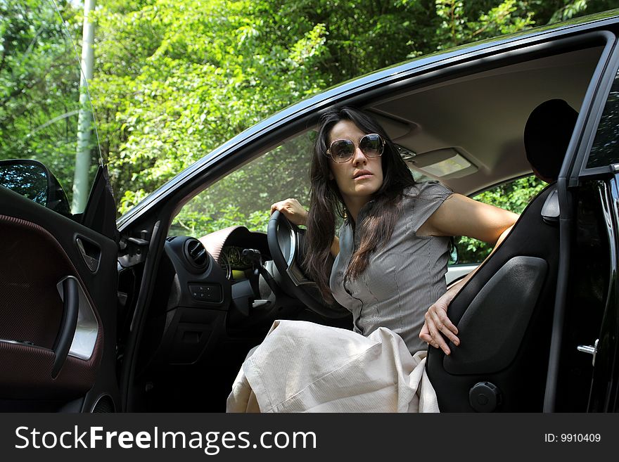 Beautiful girl seated in a car in a forest. Beautiful girl seated in a car in a forest