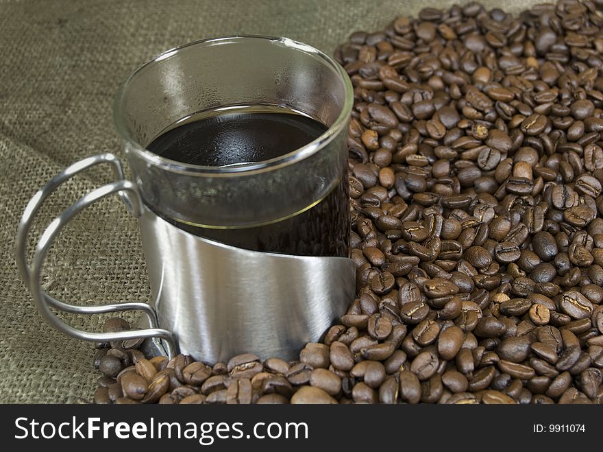 A cup of fresh coffee surrounded by coffee beans. A cup of fresh coffee surrounded by coffee beans