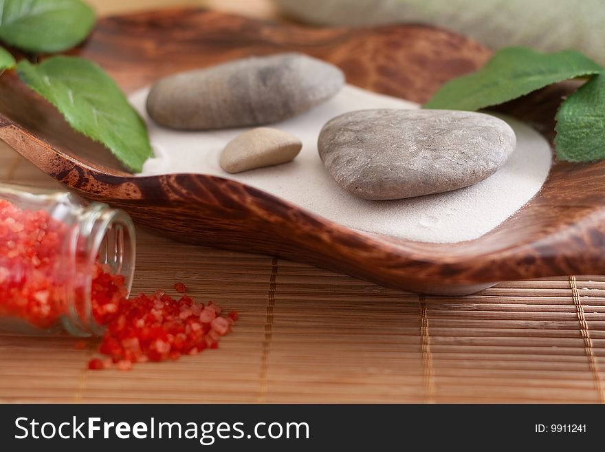 Massage stones on sand in a bowl and red bath salt. Massage stones on sand in a bowl and red bath salt