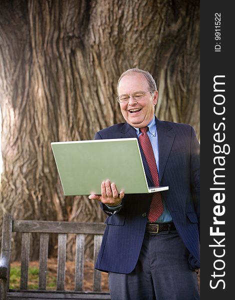 A business man laughs while working on his laptop computer. A business man laughs while working on his laptop computer