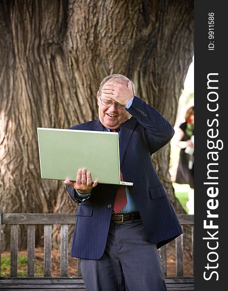 Surprised Man working on his laptop on park bench. Surprised Man working on his laptop on park bench