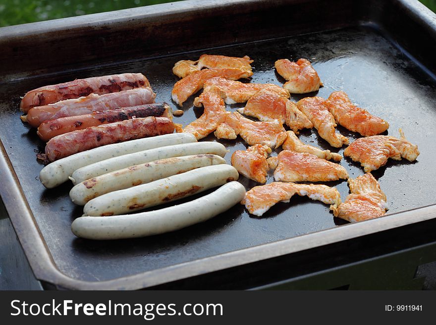 Meat and sausages on black grill. Meat and sausages on black grill