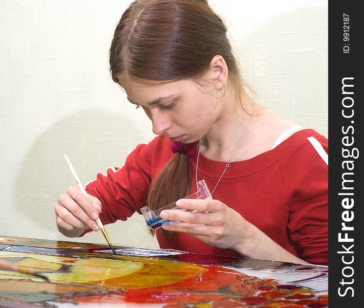 Young woman painting on the glass surface with vitrage dye. Young woman painting on the glass surface with vitrage dye