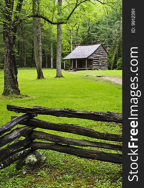 Cottege in forest with fence around it