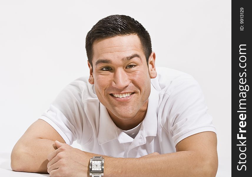 A young man is isolated in a white room.  He is wearing a white T-shirt and is smiling at the camera.  Horizontally framed shot. A young man is isolated in a white room.  He is wearing a white T-shirt and is smiling at the camera.  Horizontally framed shot.