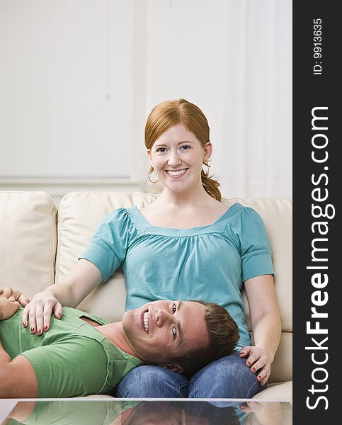 Attractive man lying down on a couch with his head in a woman's lap. Vertically framed photo. Attractive man lying down on a couch with his head in a woman's lap. Vertically framed photo.