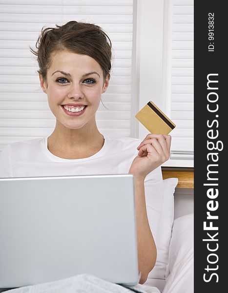 Attractive woman holding credit card with laptop and smiling at the camera. Vertically framed. Attractive woman holding credit card with laptop and smiling at the camera. Vertically framed.