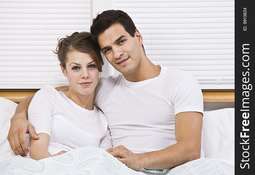 Male and female attractive couple snuggling in bed, horizontally framed. Male and female attractive couple snuggling in bed, horizontally framed