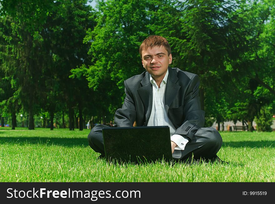 Young successful businessman resting in a park on the grass. Young successful businessman resting in a park on the grass