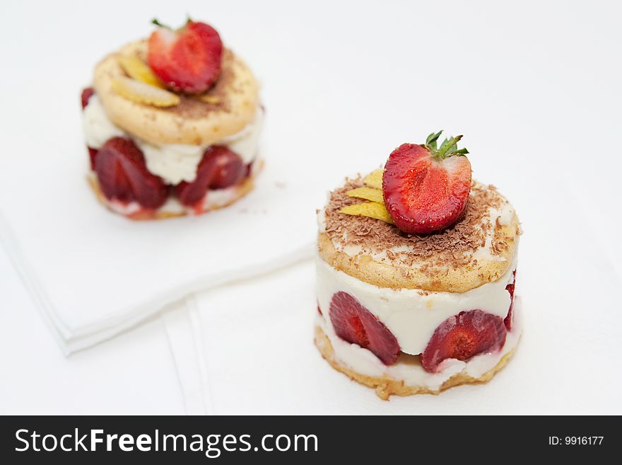 Strawberry cheesecakes with mascarpone cream decorated with chocolate chips and a half a strawberry