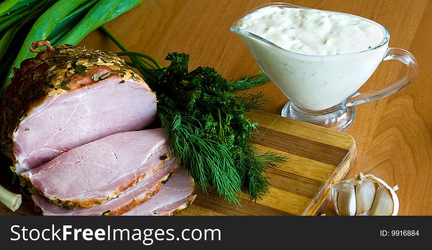 Slices of ham, potherbs and salad of green vegetables on the kitchen table. Slices of ham, potherbs and salad of green vegetables on the kitchen table