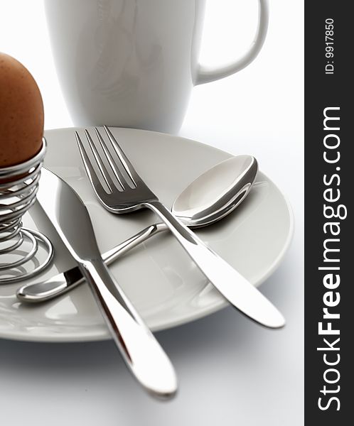 Silver cutlery and an egg on a white plate. Silver cutlery and an egg on a white plate