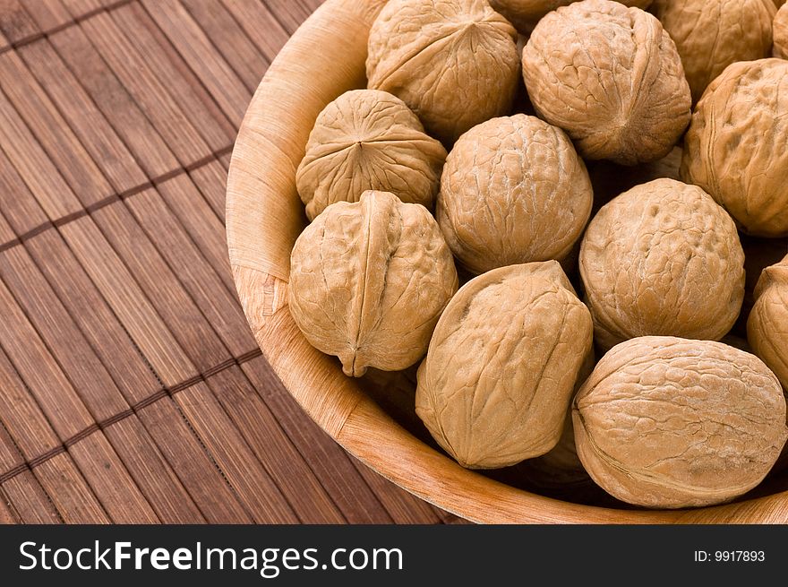 Bunch of walnuts in a bowl, over a bamboo mat. Bunch of walnuts in a bowl, over a bamboo mat.