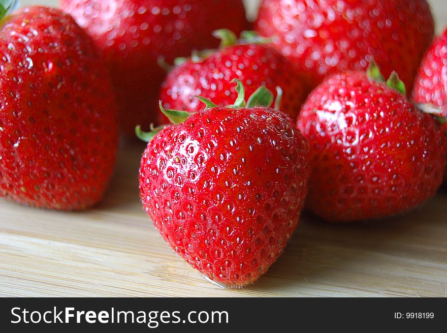 Fresh, plump red strawberries on wooden board.