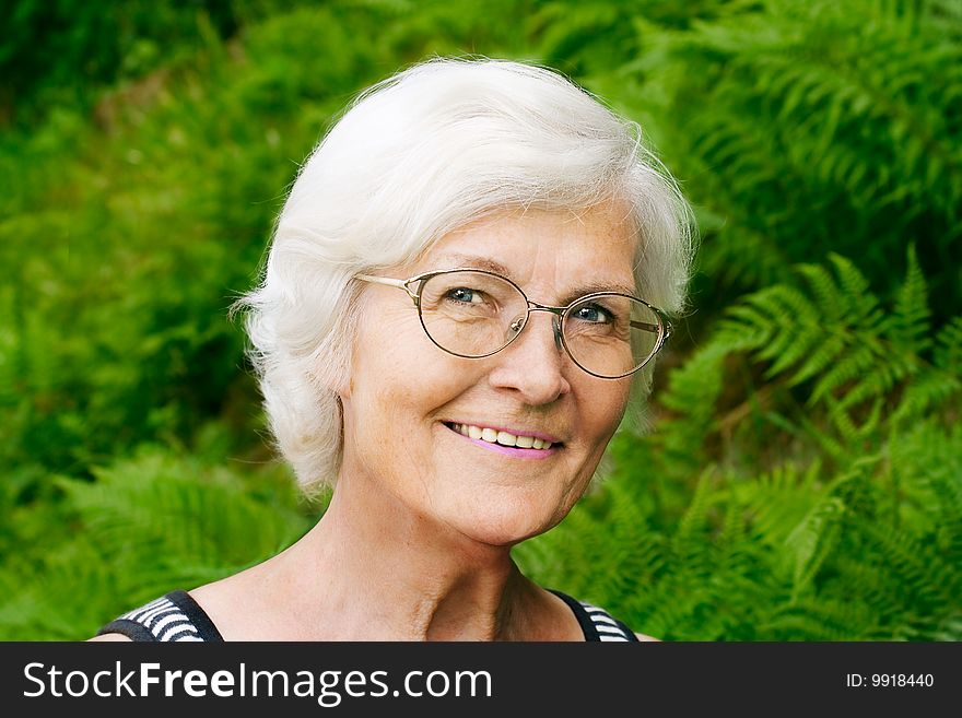 Senior woman portrait, outdoor, in front of fern,smiling to camera. Senior woman portrait, outdoor, in front of fern,smiling to camera