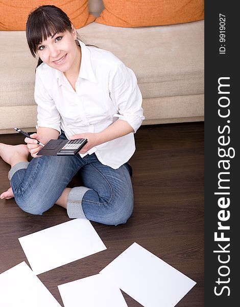 Happy young woman with calculator at home. Happy young woman with calculator at home
