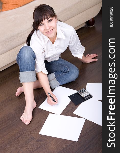Happy young woman with calculator at home. Happy young woman with calculator at home
