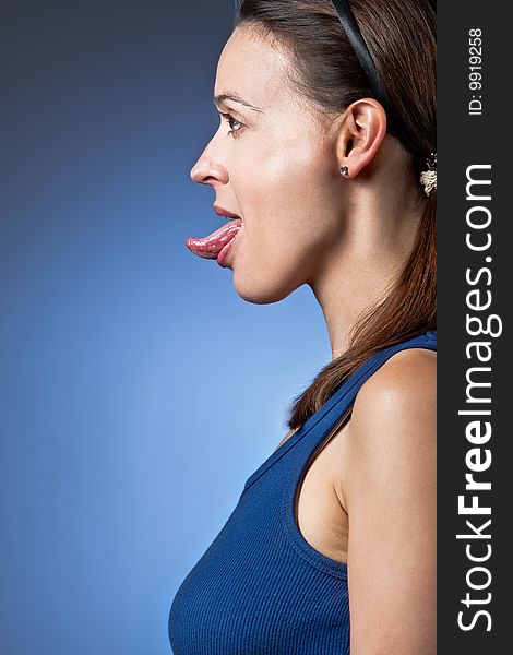 A young woman poking out her tongue in profile. A young woman poking out her tongue in profile.