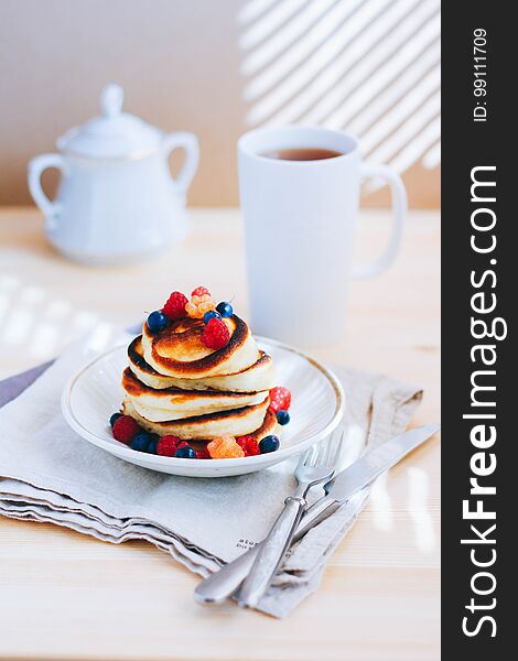 Breakfast, lush pancakes with fresh berries, raspberries and blueberries and a cup of tea