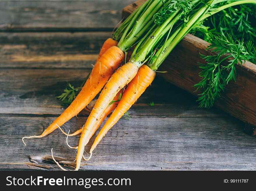 Fresh carrots with green tops in a wooden box, on a wooden background, harvest, autumn. Fresh carrots with green tops in a wooden box, on a wooden background, harvest, autumn