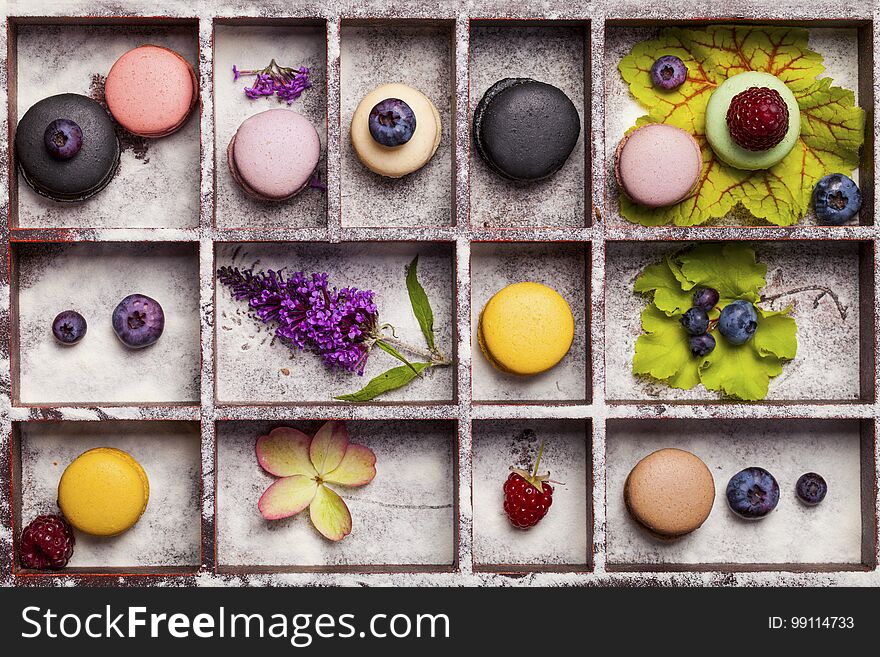 Variety of colorful french sweet dessert - les macarons with flowers and berries.