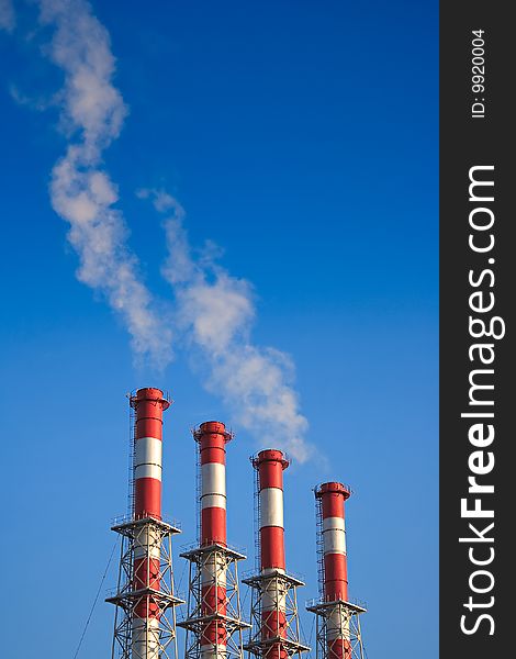 Four factory chimney smoking  on a background blue Sky