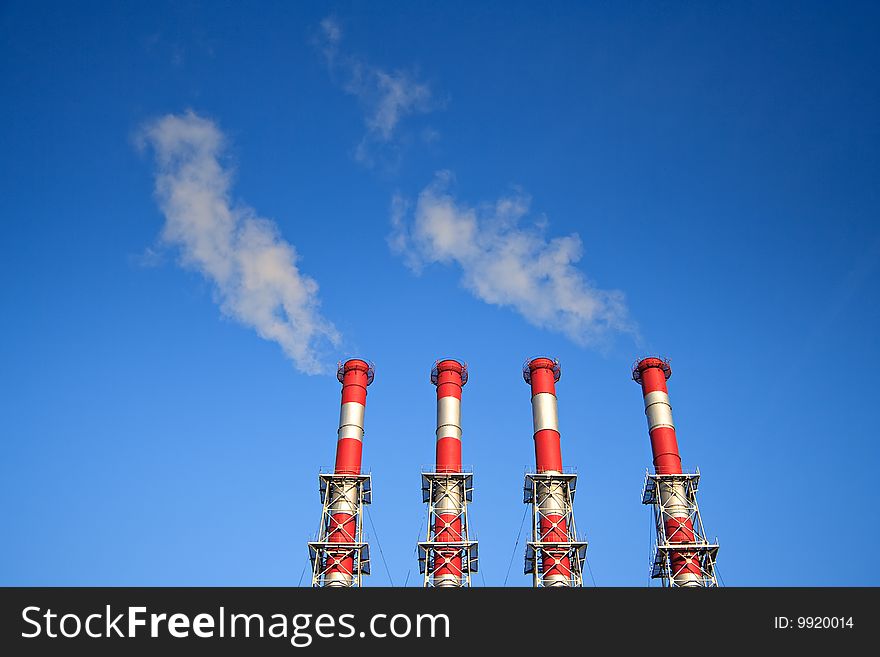 Four factory chimney smoking  on a background blue Sky